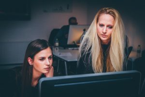 A woman mentors another woman while looking at a computer