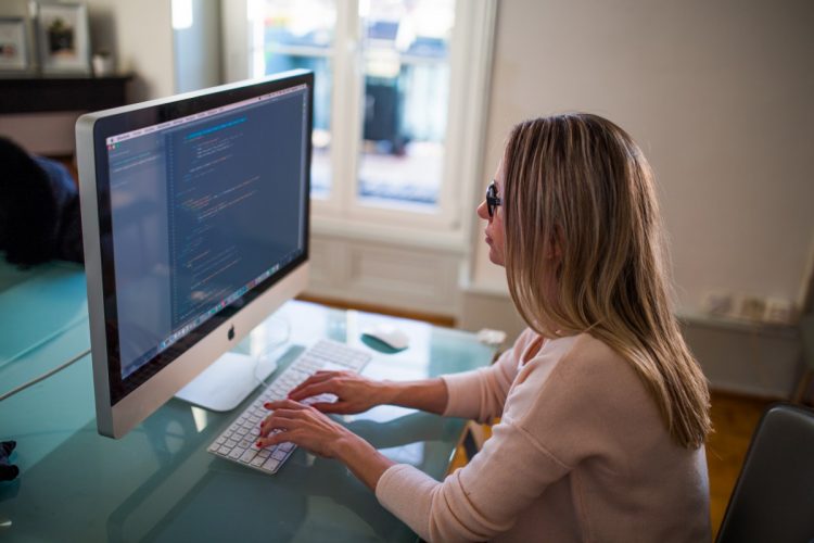 Woman coding on iMac computer