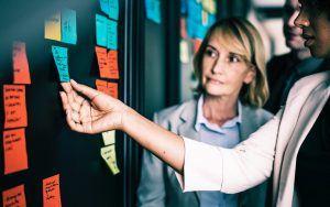 Women holding sticky notes at blackboard