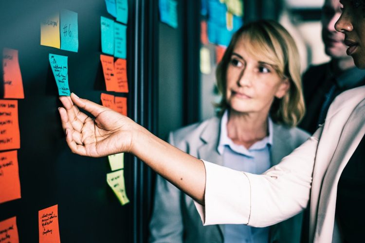 Women holding sticky notes at blackboard